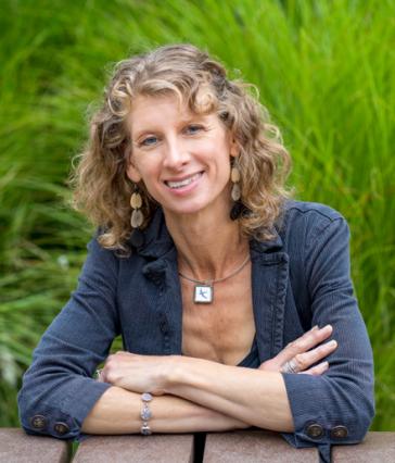 Woman smiles with arms crossed at a table