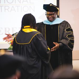 Professor embraces student at Educational Administration hooding ceremony.