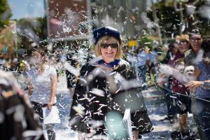 President Jane Close Conoley walking through confetti while wearing academic regalia