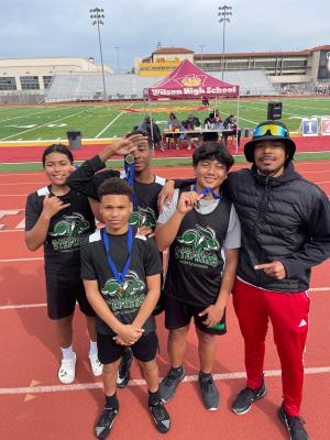 One of the Cooper twins with a group of young athletes posing with medals