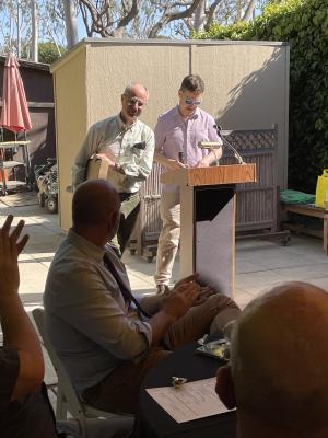 Two people are standing at a podium and facing the audience 