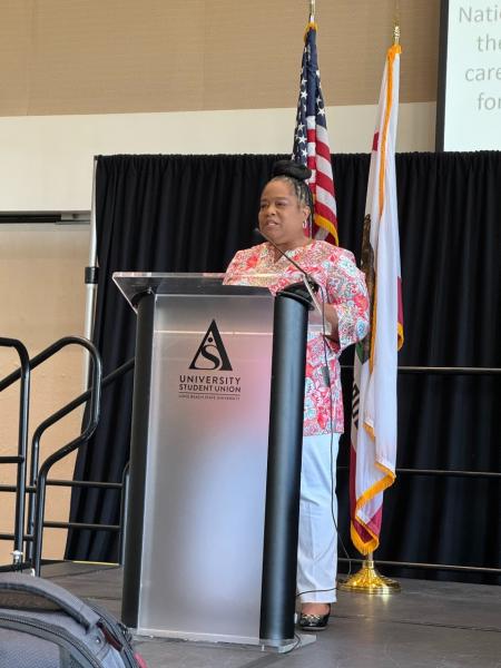 A woman stands at a podium and delivers a speech.