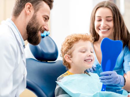 young dental patient smiling and examining teeth