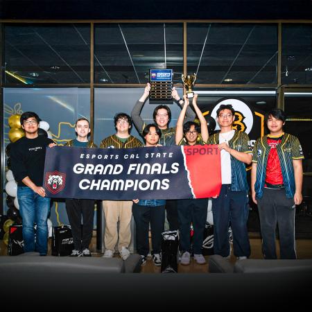 CSULB esports team grand finals champions 2025 Group of eight people hold a "Grand Finals Champions" banner and two trophies at an esports event