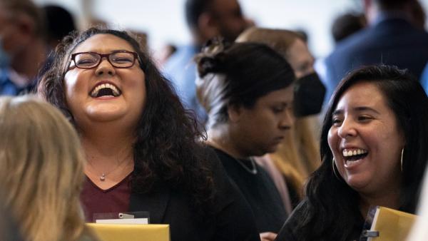 Two staff members laugh at the staff service awards in 2023. 