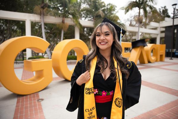 Graduate in front of Go Beach sign