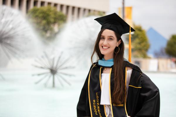 Graduate in front of Brotman hall  fountain