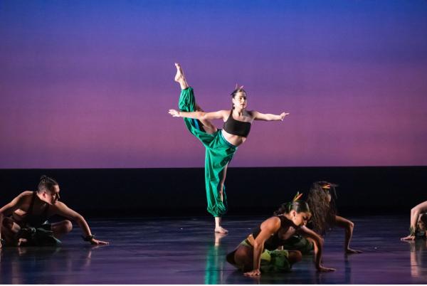 A dancer dances on stage with other performers.