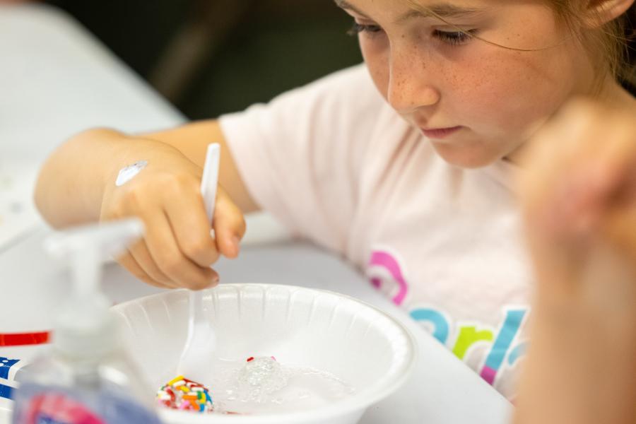 A girl peers into a bowl of soapy water which holds mock viruses she made in CSULB's Virology Lab 