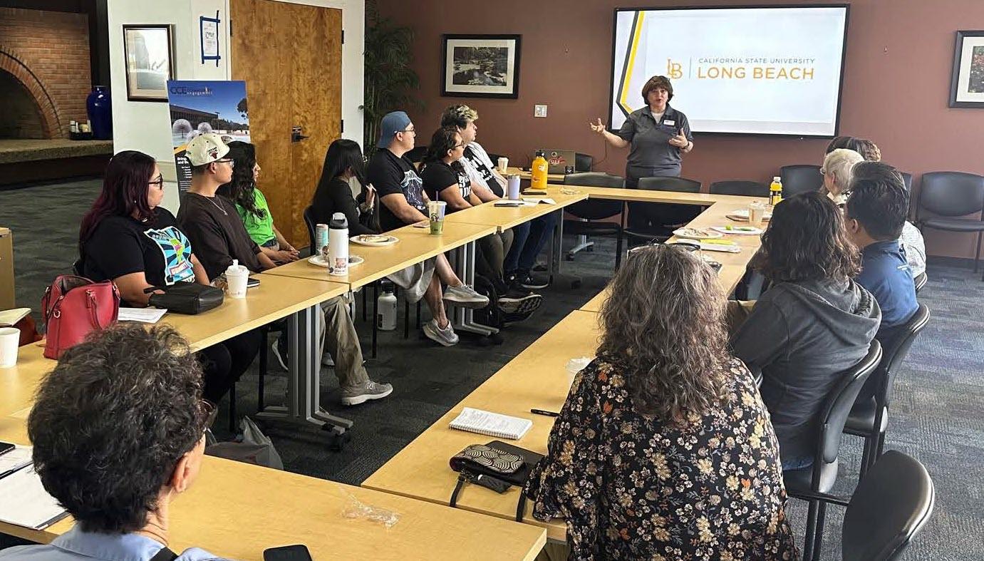 Group of adults sitting at a conference room table while a woman presents