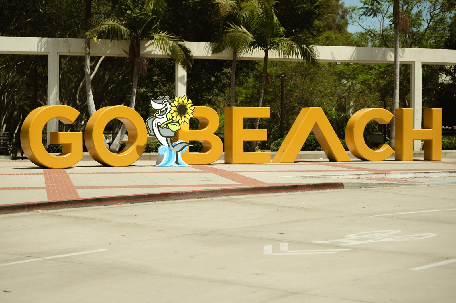 Elbee with a sunflower in front of Go Beach sign