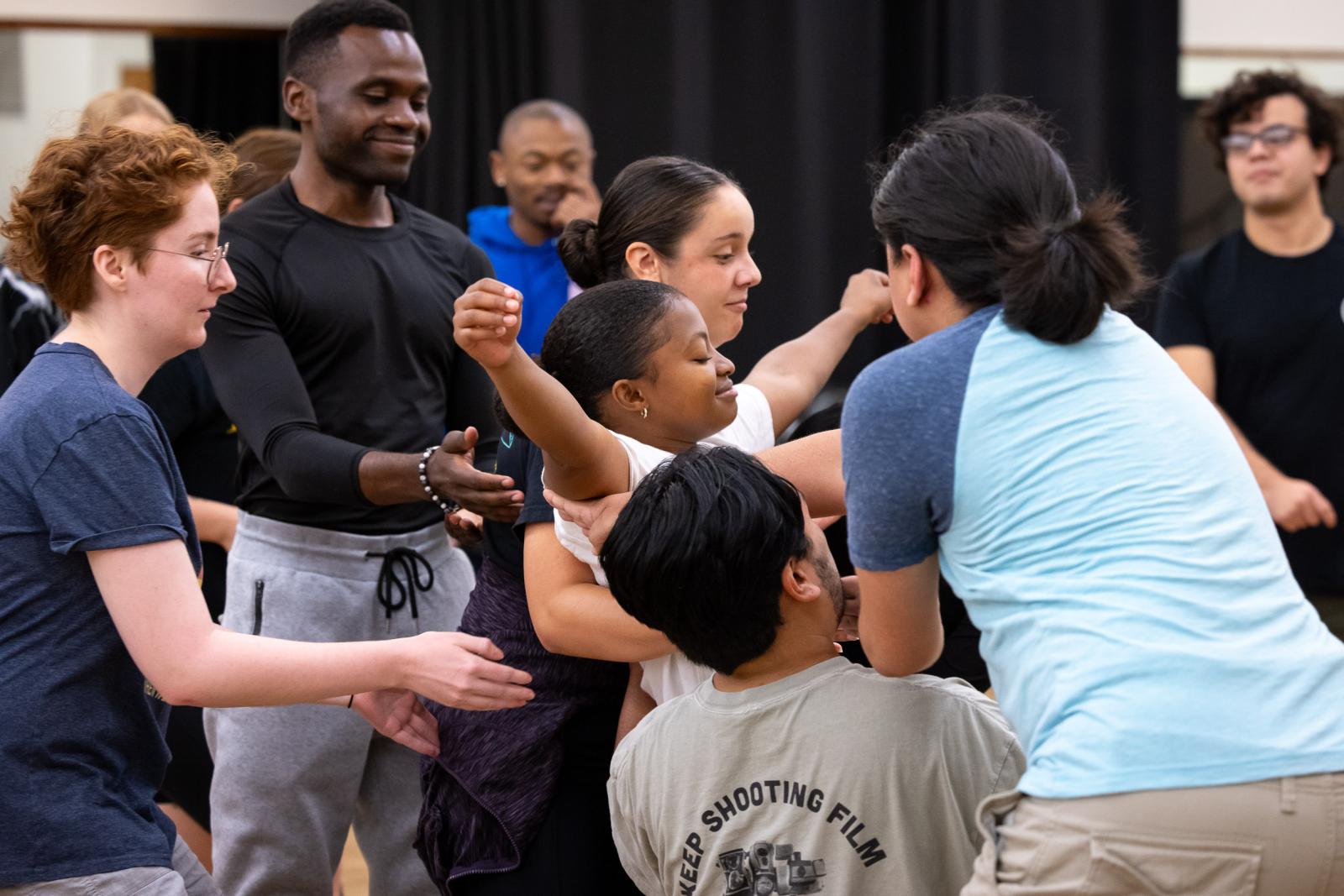 Theater students practice carrying a student after she does a pretend fall