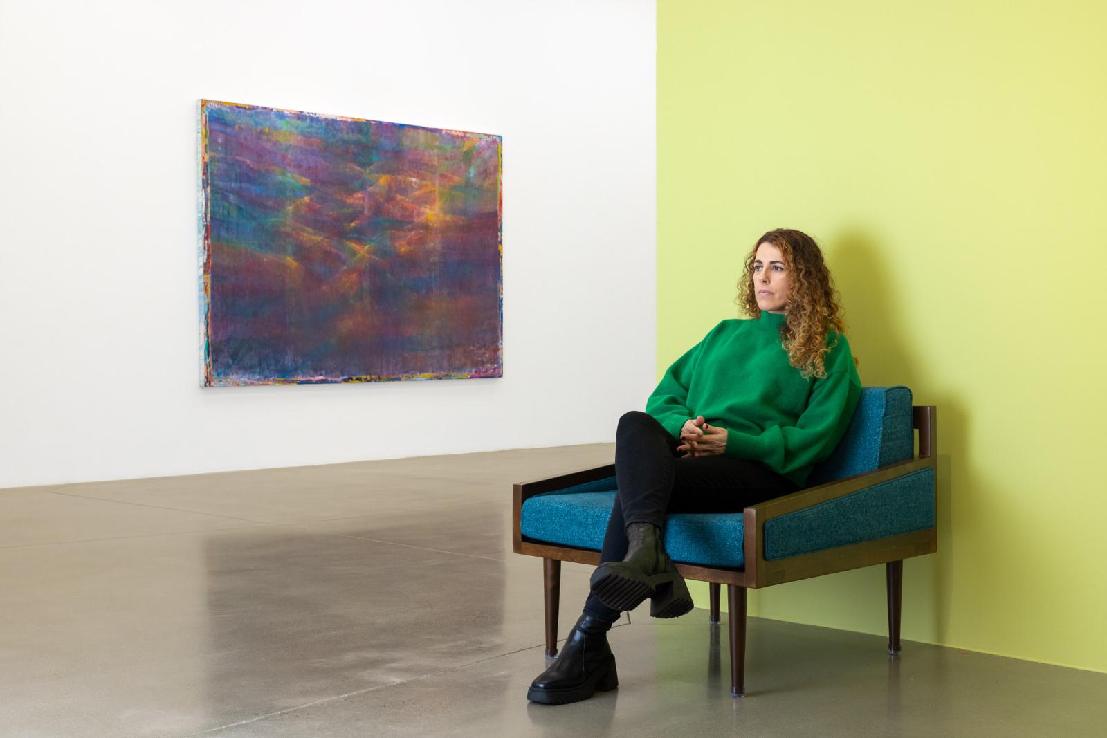 Rema Ghuloum sits in front of her painting, "Hayat," at the Kleefeld Museum