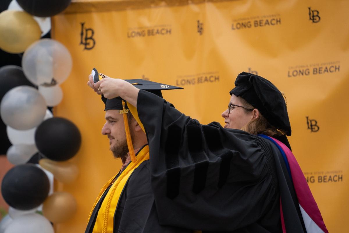 Dr. Hall places grad cap on student