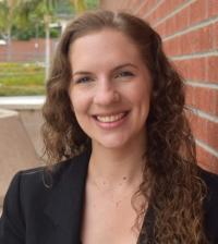 Portrait of a woman standing in front of a brick wall.