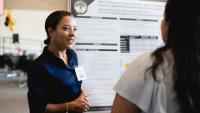 Student giving presentation in front of poster.